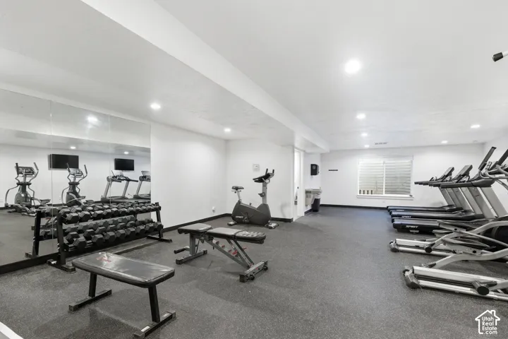 Dedicated fitness area with rubber flooring, recessed lighting, and a mirrored wall