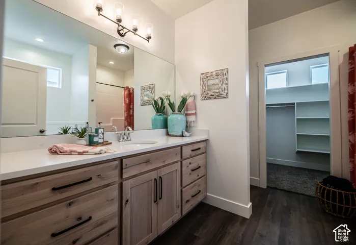 Wood-finish flooring with a light wood-finish vanity, white countertop, and single basin sink