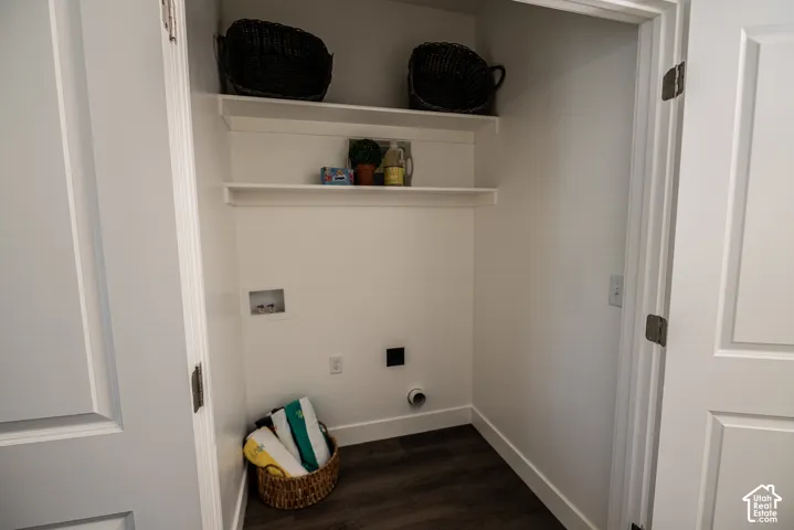Laundry closet with wood-finish flooring, two white shelving units, and appliance hookups