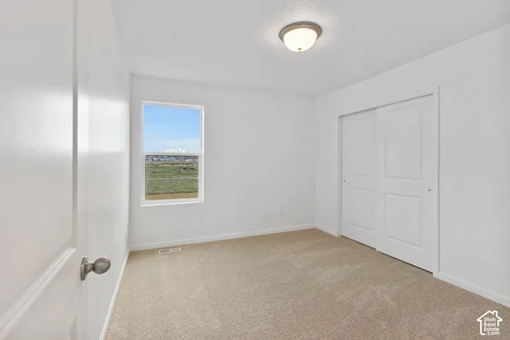 Neutral tone carpeting, white walls, and a window with mountain scenery