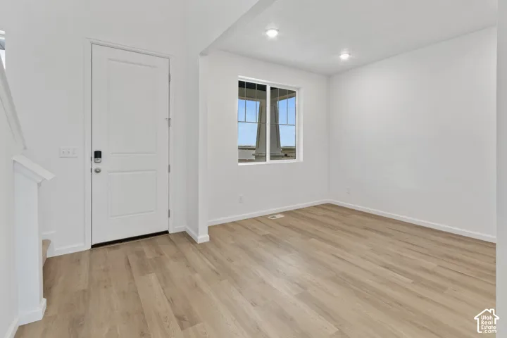 Wood-finish flooring, white paneled door, recessed lighting, and a multi-pane window