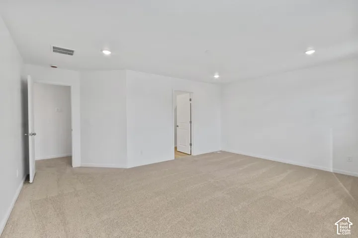 Neutral-toned wall-to-wall carpeting with recessed lighting and white painted walls