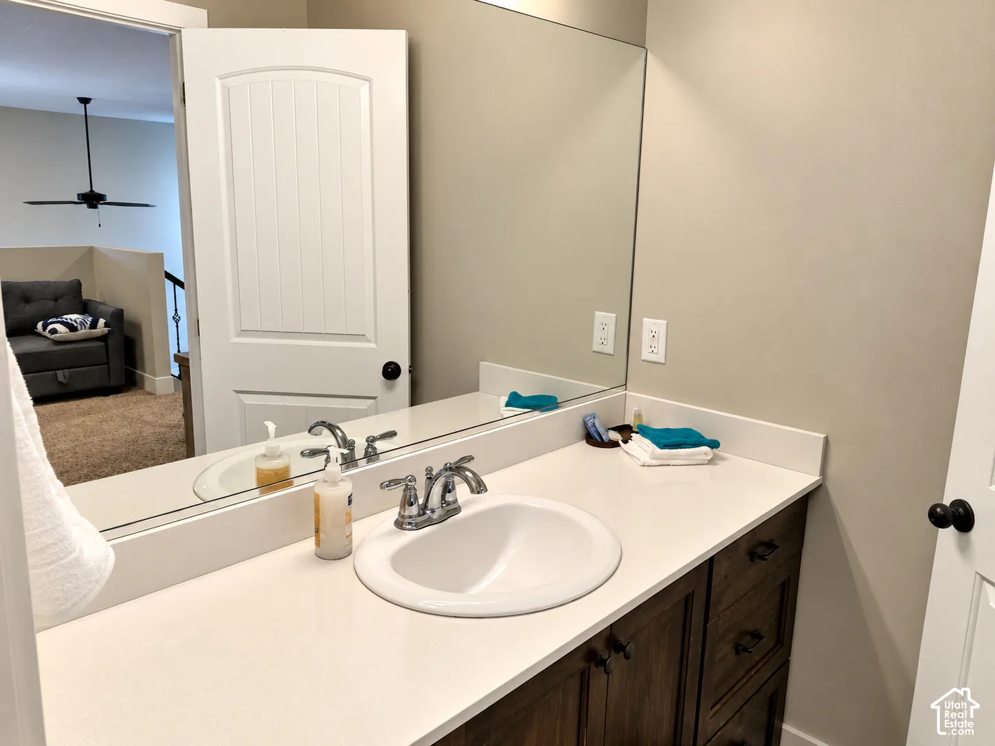 Vanity featuring a stone-composite countertop, undermount sink with a polished chrome dual-handle faucet, and dark-finish cabinetry with matte black hardware, accompanied by a full-width wall mirror