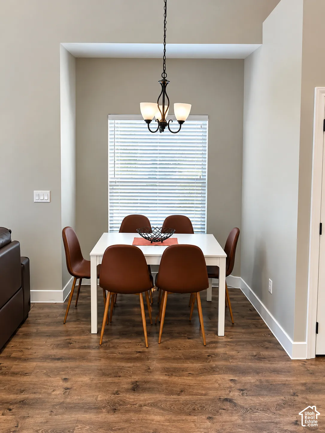 Recessed dining nook featuring wood-finish flooring, neutral wall tones, and a traditional multi-arm pendant light fixture