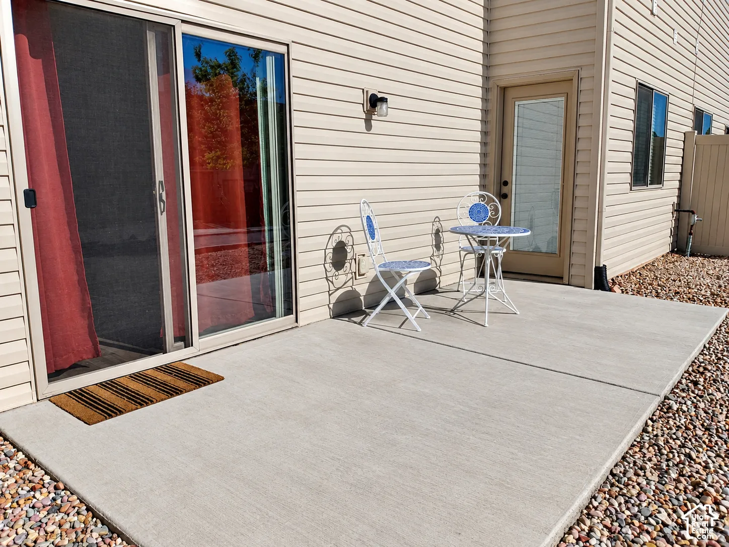 Concrete patio featuring horizontal siding exterior, sliding glass door, and dedicated utility door