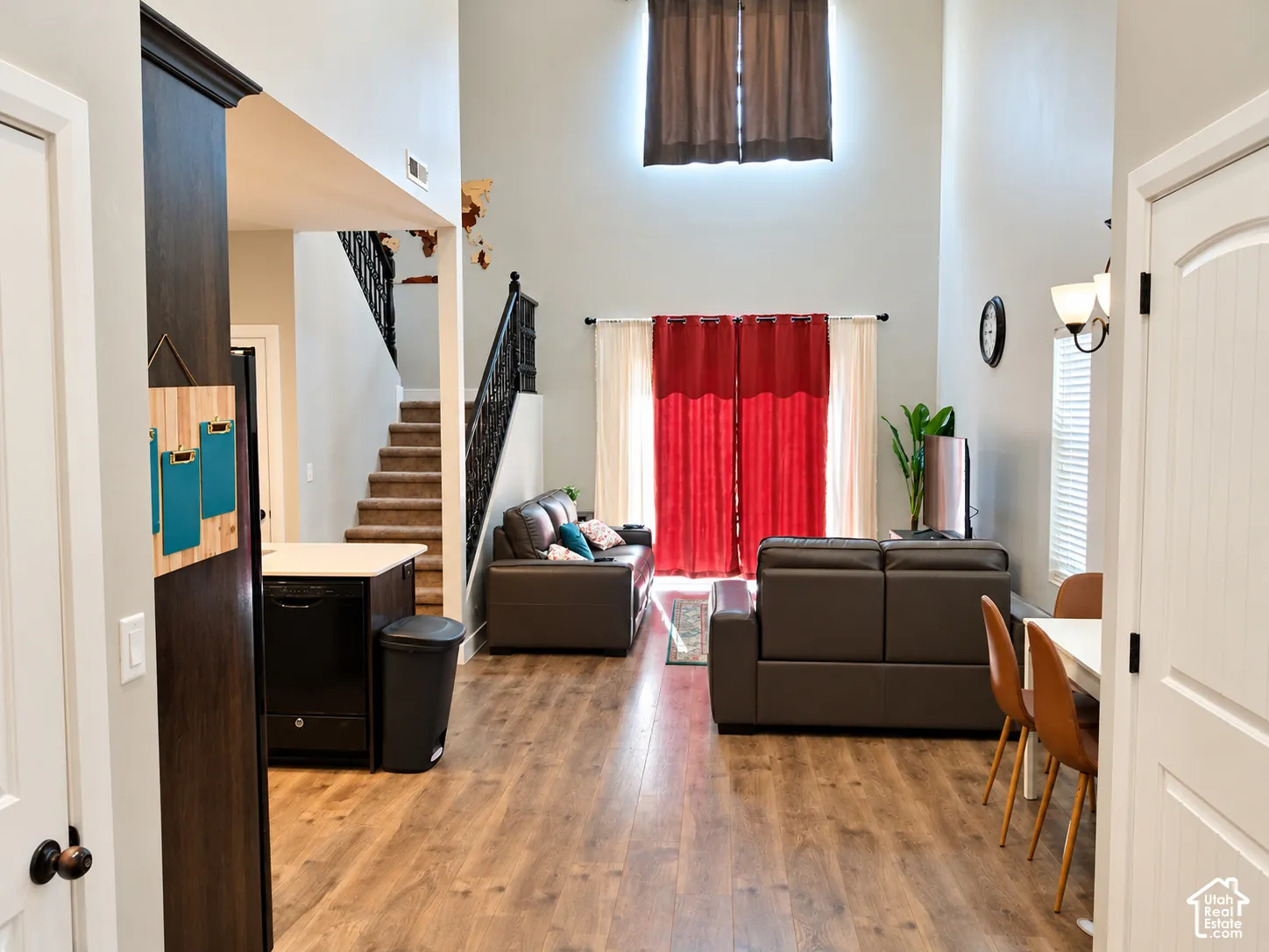 Vaulted ceilings, wood-finish flooring, staircase with decorative metal railing, and neutral wall tones