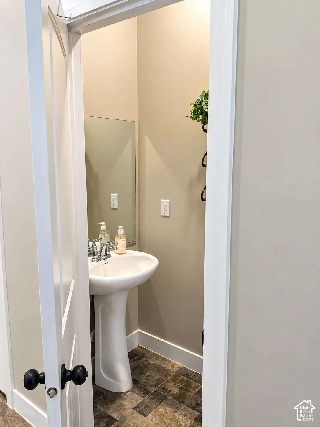 Pedestal sink featuring a polished chrome faucet, wall-mounted mirror, and tile flooring