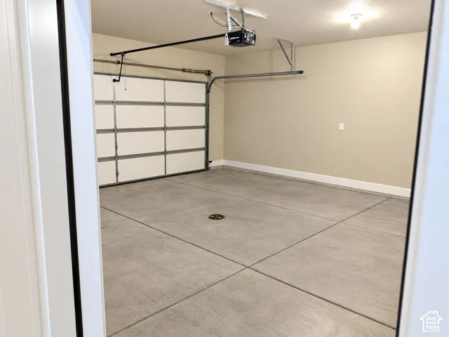 Attached garage featuring a concrete floor, automated garage door opener, and finished wall surfaces