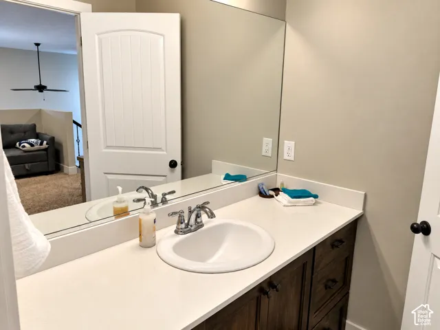 Vanity featuring a stone-composite countertop, undermount sink with a polished chrome dual-handle faucet, and dark-finish cabinetry with matte black hardware, accompanied by a full-width wall mirror