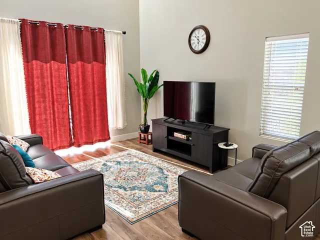 Vaulted ceilings, wood-finish flooring, and natural light entering through vertical windows with horizontal blinds