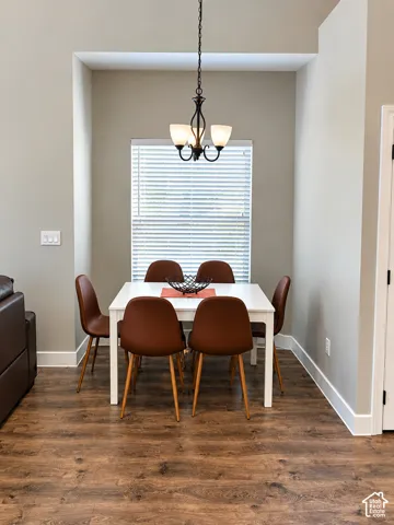 Recessed dining nook featuring wood-finish flooring, neutral wall tones, and a traditional multi-arm pendant light fixture