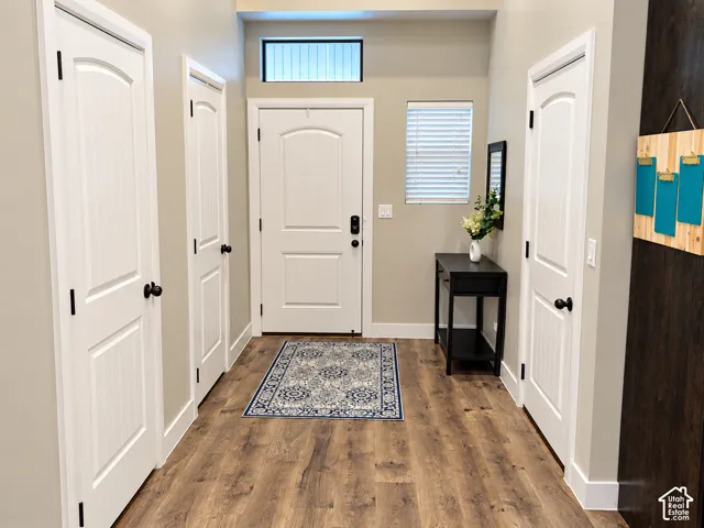 Entryway featuring wood-finish flooring, two-panel arched interior doors with matte black hardware, and an arched entry door with a rectangular transom window