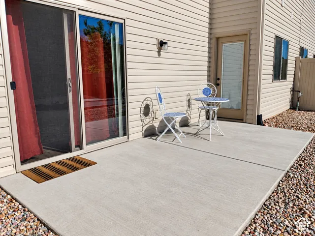 Concrete patio featuring horizontal siding exterior, sliding glass door, and dedicated utility door