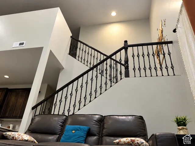 Staircase featuring dark wood-finish handrails, intricate black metal balusters, and recessed ceiling lighting