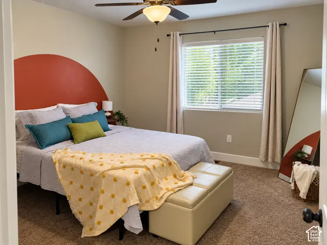 Bedroom featuring neutral wall-to-wall carpeting, a multi-blade ceiling fan with integrated lighting, and a single-pane window with horizontal blinds