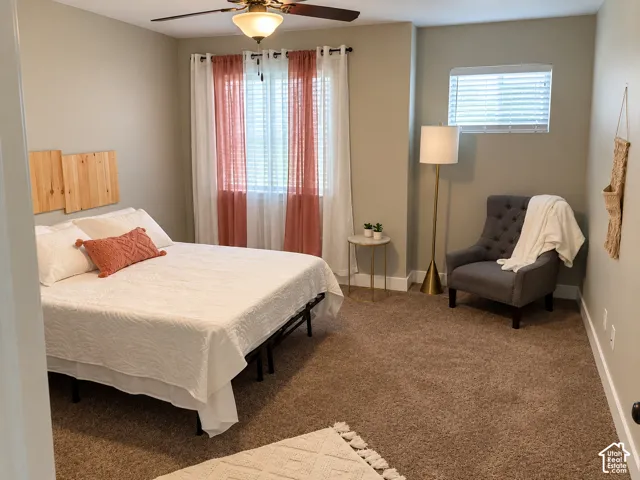 Neutral-toned interior room featuring wall-to-wall carpeting, an integrated ceiling fan with light fixture, and windows equipped with blinds