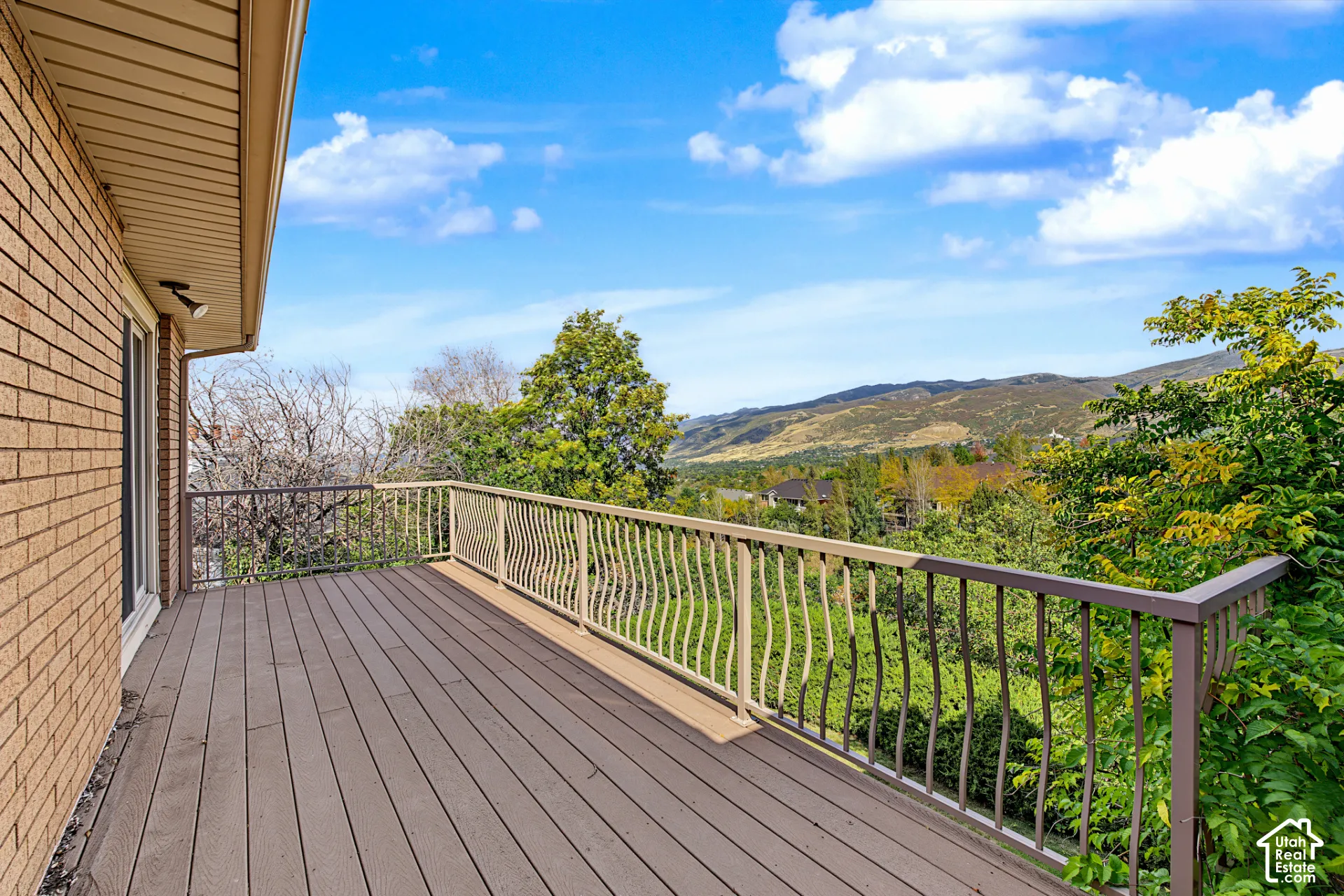 Expansive outdoor deck with composite decking and decorative metal railings, complemented by a brick exterior