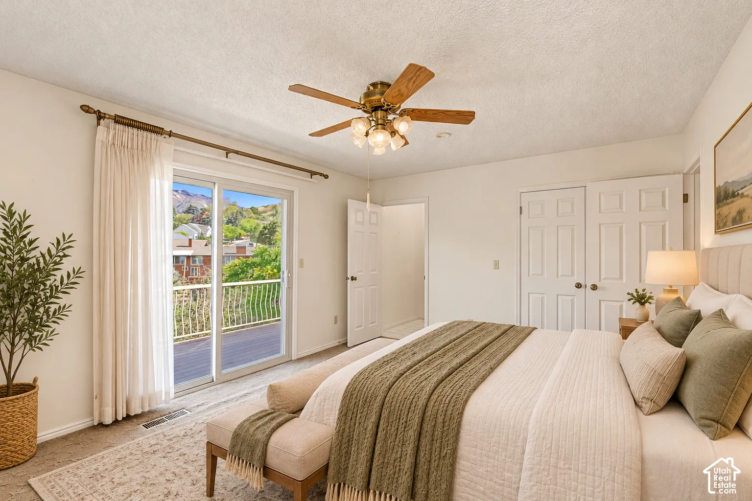 Owner bedroom -Sliding glass door leading to a private outdoor balcony with metal railings, featuring a ceiling fan with light fixture, and double bi-fold closet doors