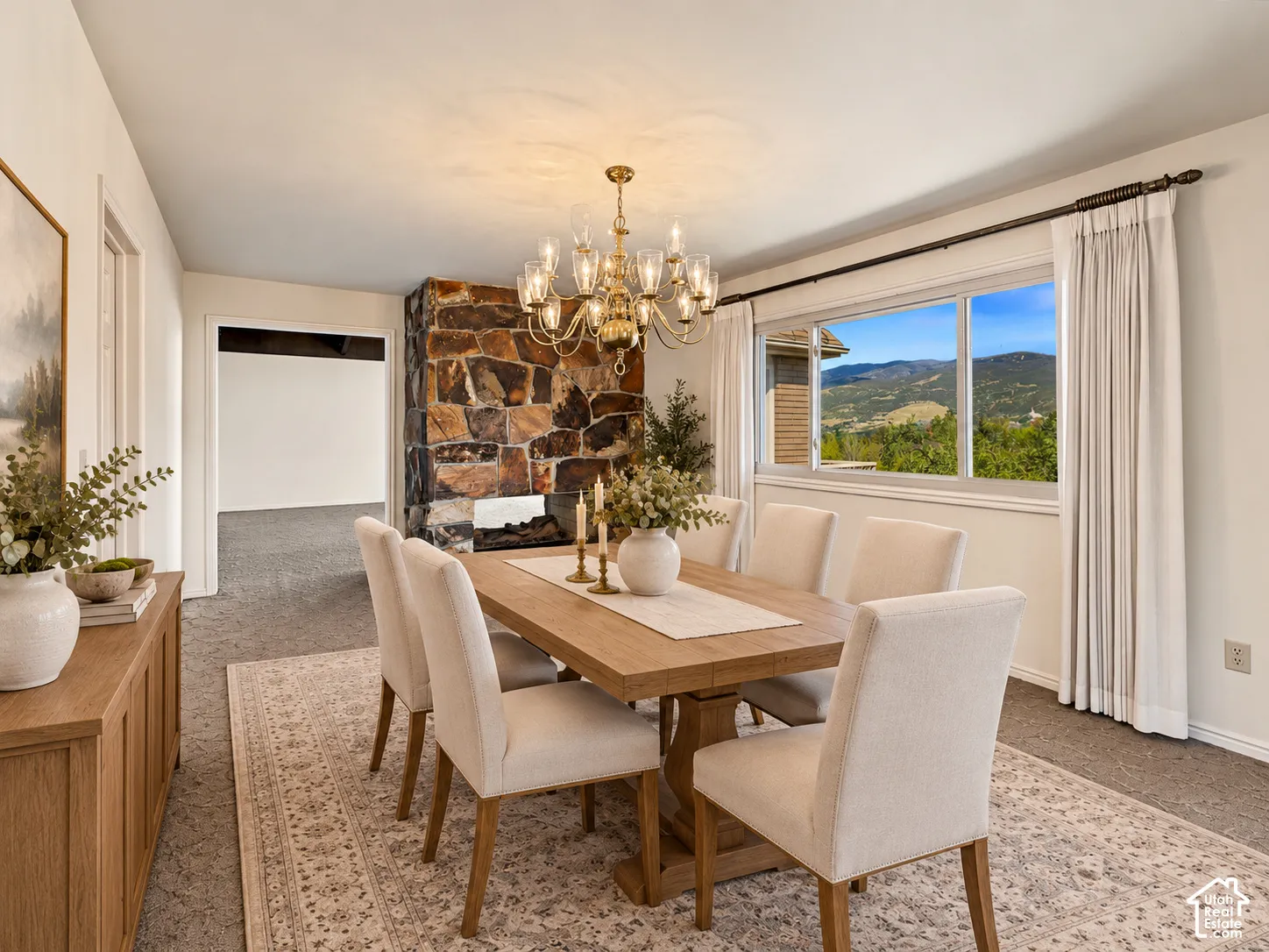 Stone-clad fireplace with built-in hearth, multi-pane window, and a chandelier lighting fixture