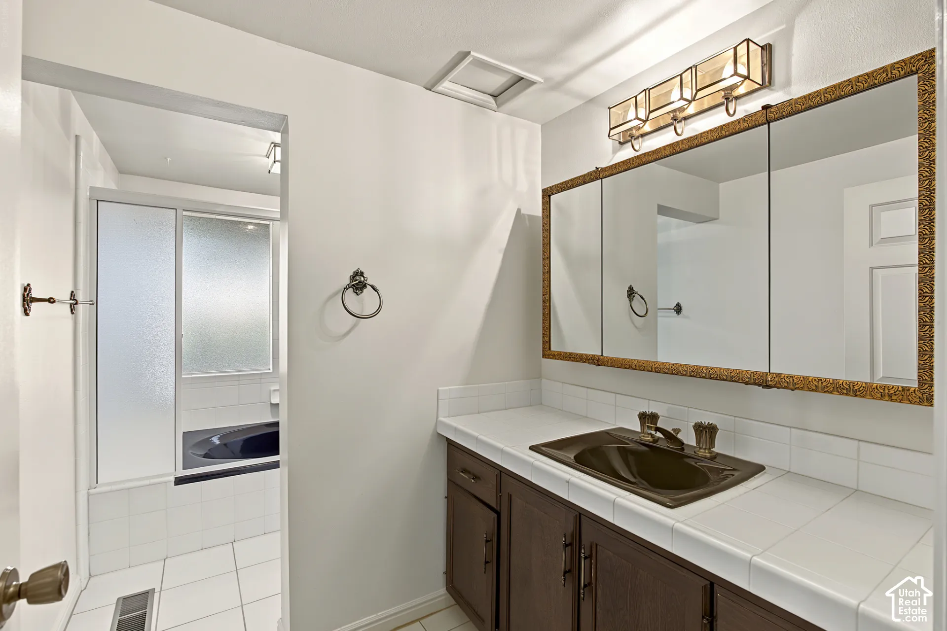 Vanity with dark wood cabinetry, integrated sink, and bronze-finish fixtures
