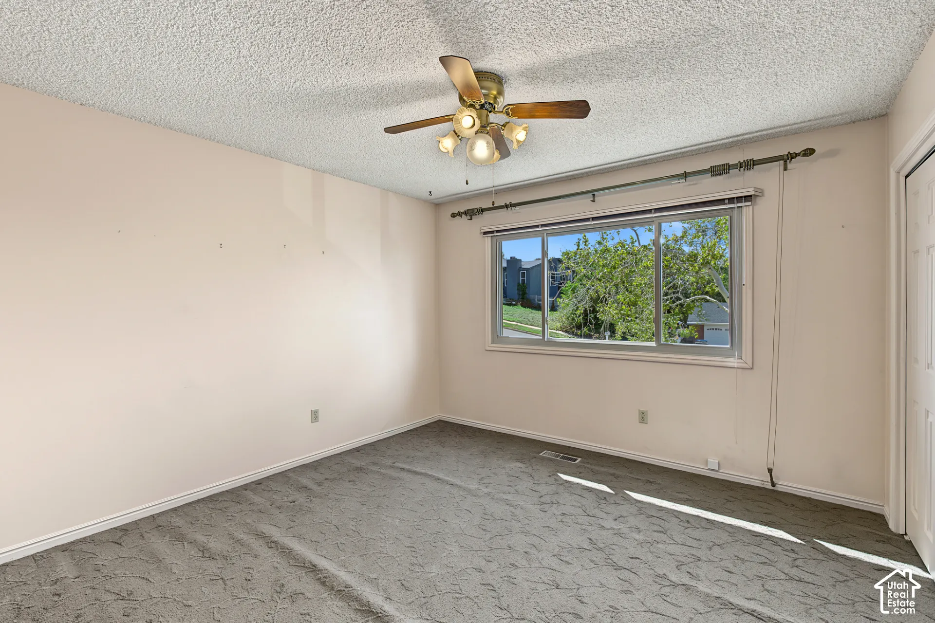 Carpeted room featuring a ceiling fan with integrated lighting, a window with horizontal blinds, and a built-in closet