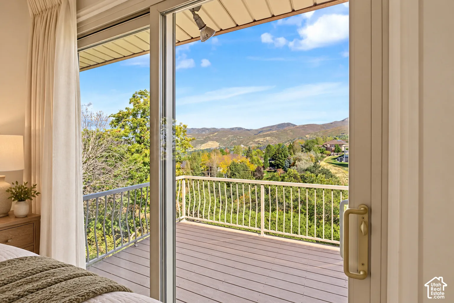 Owner bedroom-Sliding glass door leading to a private outdoor deck with metal railing, featuring a wood-finish floor and mountain scenery