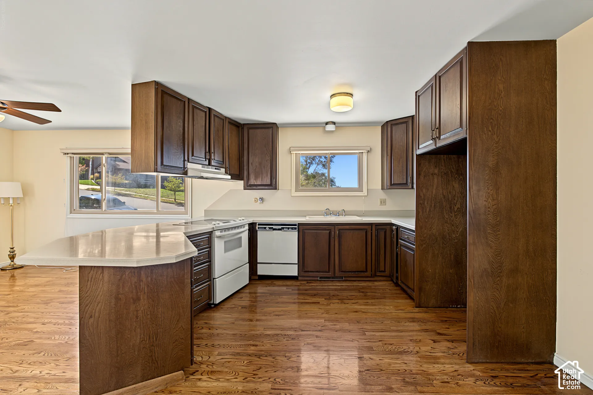 Kitchen featuring wood-finish flooring, extensive wood cabinetry, white countertops, and a built-in cooktop with oven