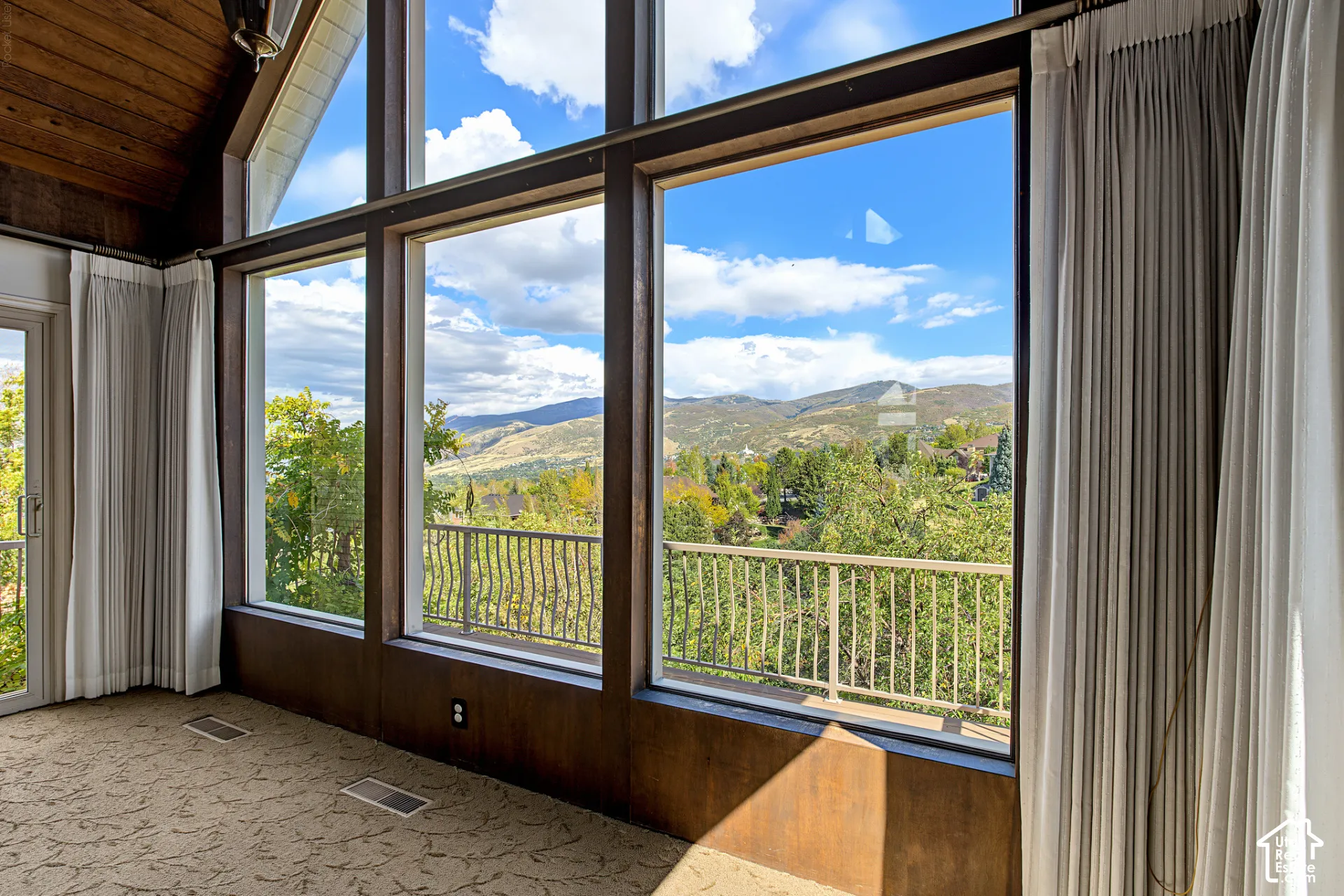 Expansive windows with dark wood-finish framing, providing abundant natural light and exterior scenery