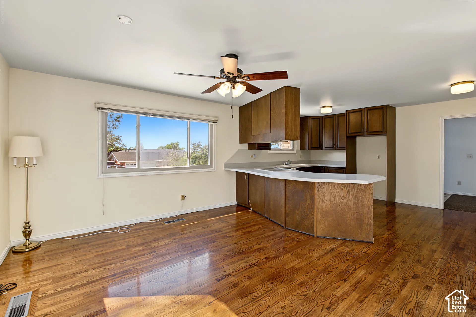 Wood-finish flooring, recessed lighting, ceiling fan, white countertops, and wood-finish cabinetry
