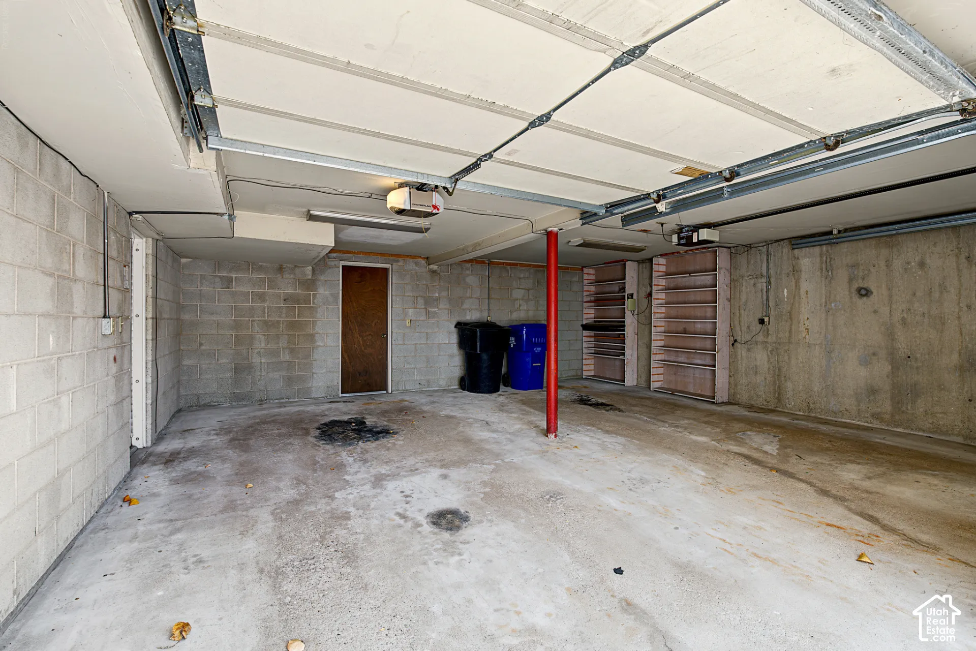 Attached garage with concrete block walls, concrete flooring, and built-in shelving