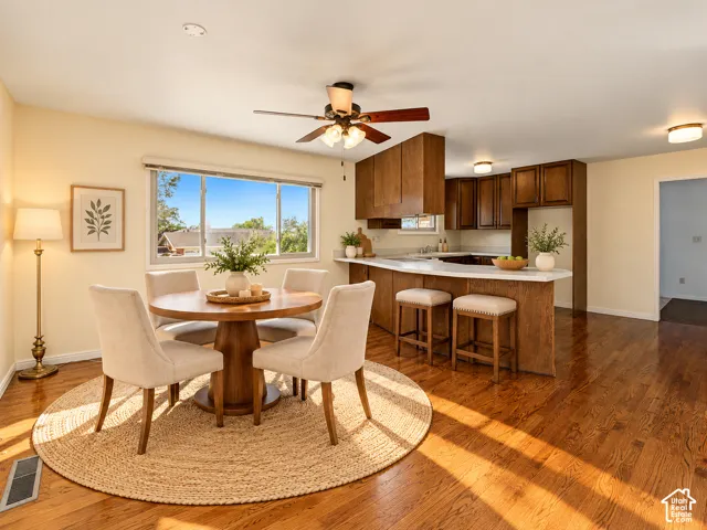 Hardwood flooring throughout, kitchen with wood-finish cabinetry, white countertops, and a breakfast bar