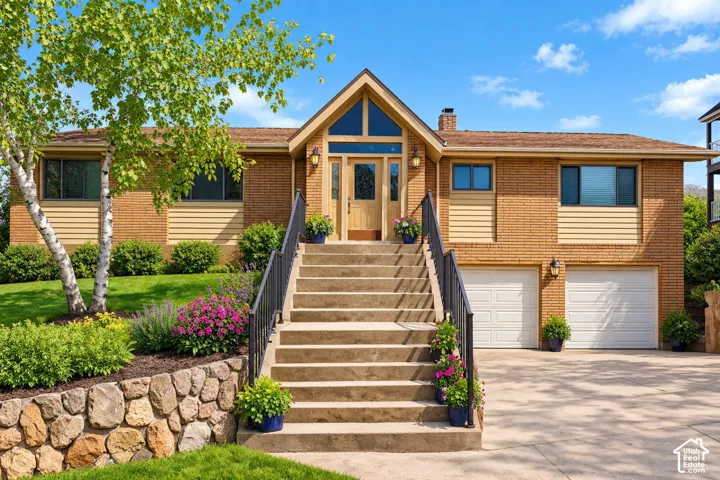 Brick and siding exterior with an arched entryway, multiple windows, and a two-car garage