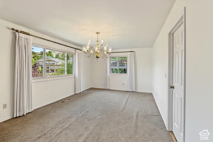 Recessed lighting, ornate brass chandelier, multiple windows, white painted walls, and a white interior door