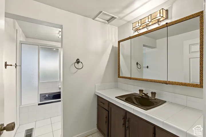 Vanity with dark wood cabinetry, integrated sink, and bronze-finish fixtures