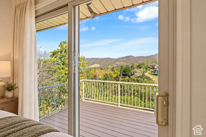Owner bedroom-Sliding glass door leading to a private outdoor deck with metal railing, featuring a wood-finish floor and mountain scenery