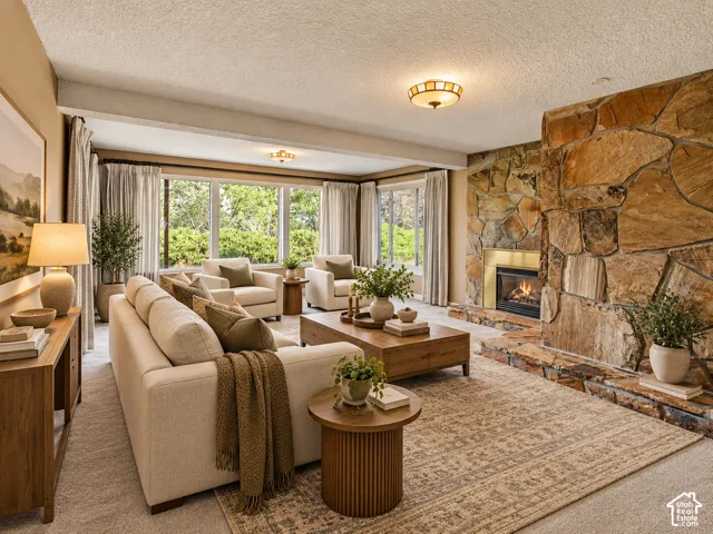 Stone-clad fireplace with a brass-trimmed firebox, large picture windows, recessed lighting, and soft carpeting