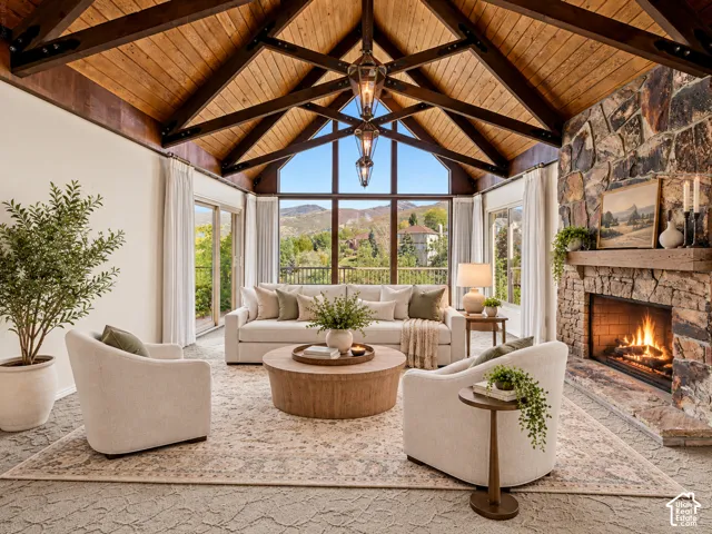 Vaulted wood-paneled ceiling with exposed beams, full-height stone fireplace, large picture windows, and sliding glass doors