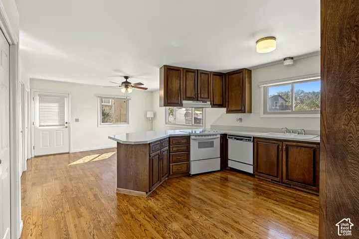 Wood-finish flooring throughout, featuring a kitchen with wood cabinetry, light countertops, and white appliances