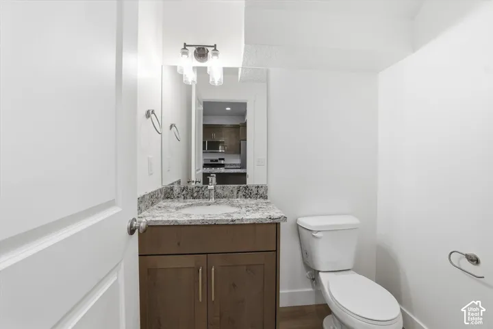 Vanity with a light-toned countertop, wood-finish cabinetry, and a contemporary mirror