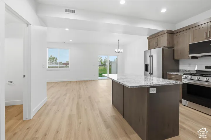 Open-concept living area with light wood-finish flooring, recessed lighting, and a modern chandelier