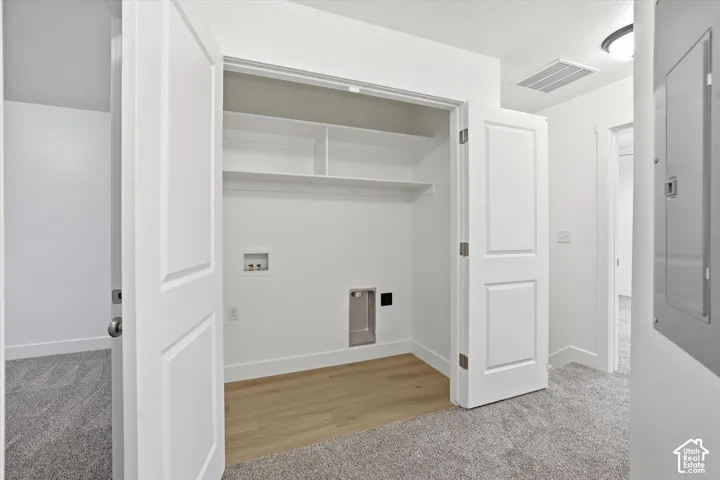 Laundry closet with wood-finish flooring, built-in shelving, and panel doors