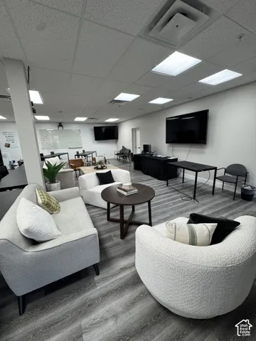 Recessed ceiling lighting, wood-finish flooring, white walls, and wall-mounted screens
