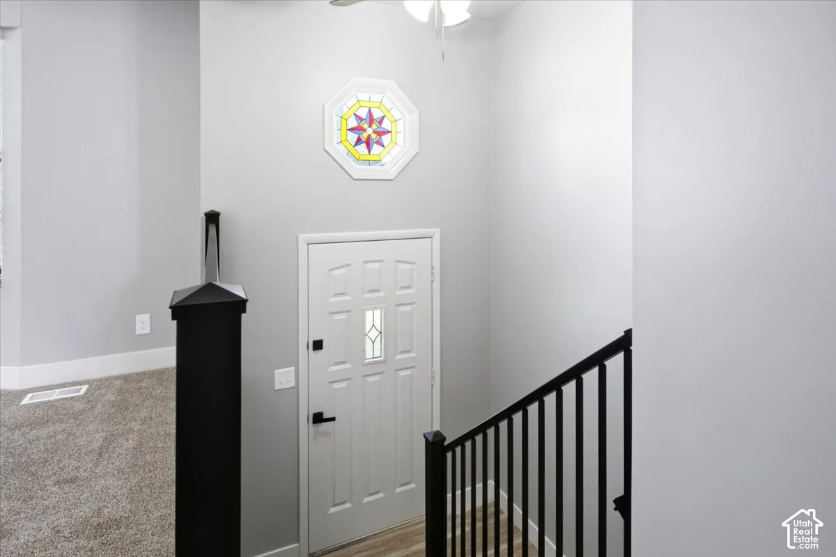 Stained glass decorative octagon window, black metal stair railing, and wood-finish flooring