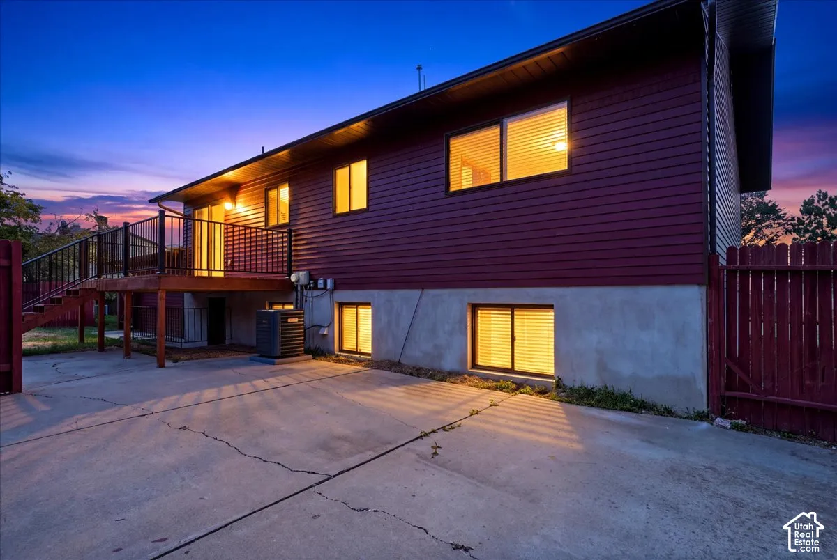 Expansive concrete patio, wood deck with black railings, and red siding exterior