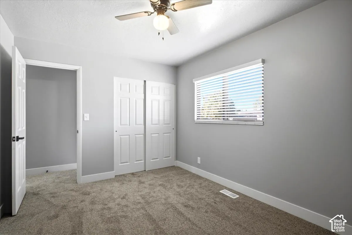 Light gray wall paint, tan carpeting, white trim, white window blinds, and a ceiling fan with integrated lighting