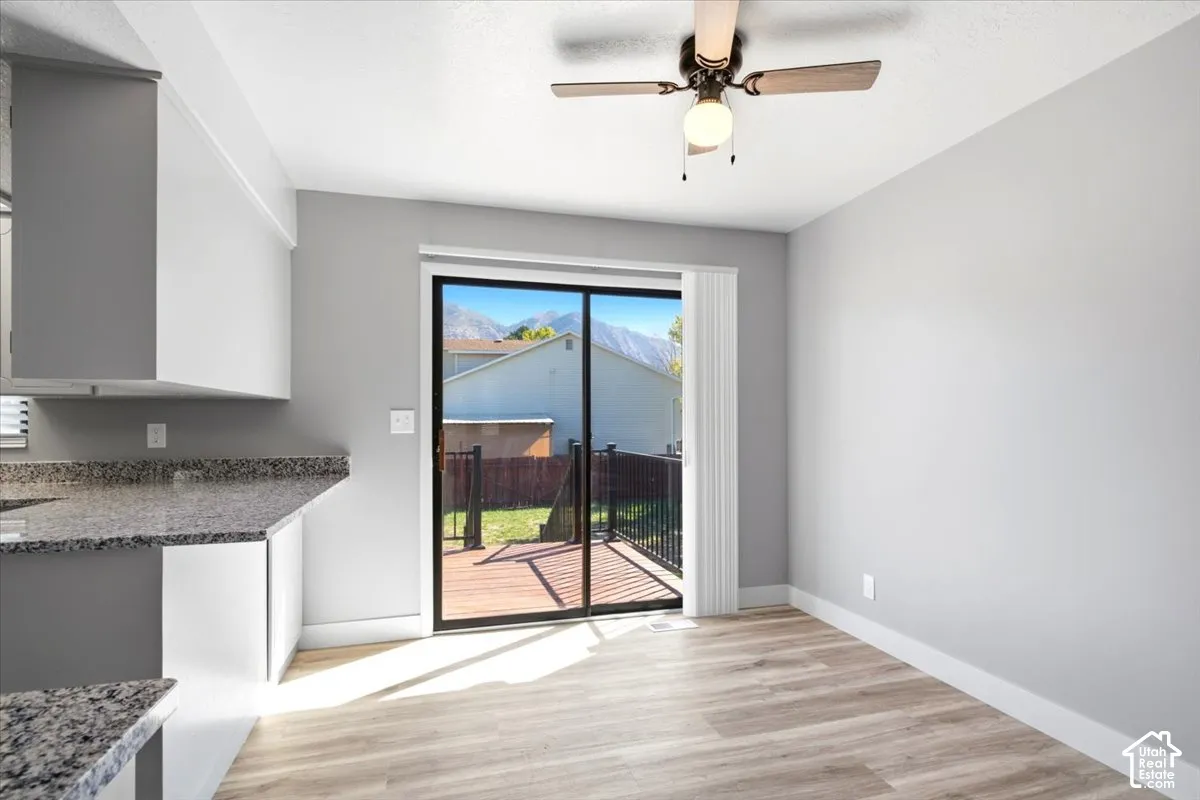 Granite-style countertops, wood-finish flooring, and a ceiling fan with integrated lighting