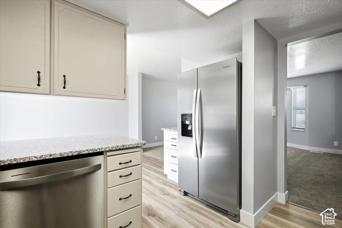 Kitchen featuring light-toned cabinetry, speckled countertops, and wood-finish flooring