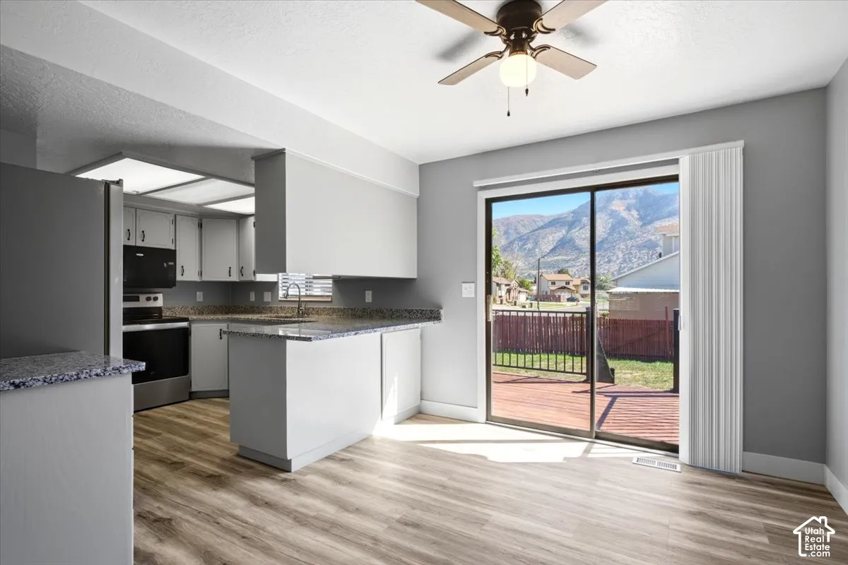 Kitchen featuring light wood-finish flooring, white cabinetry with dark countertops, and stainless steel appliances
