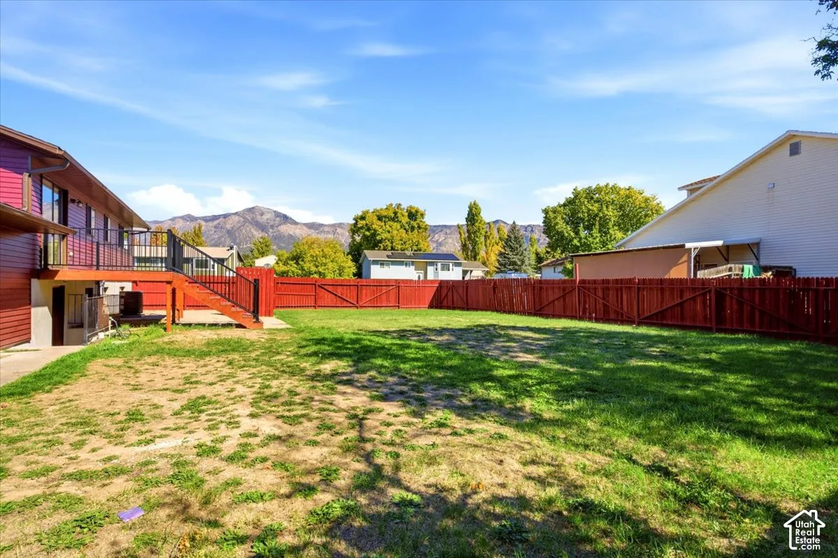 Expansive backyard featuring a red wooden fence and a multi-level deck with black railings