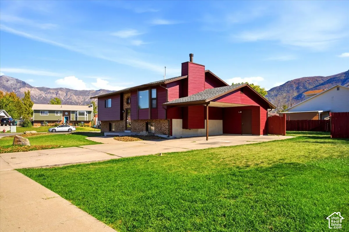 Split-level exterior with red siding, stone accents, and an attached carport